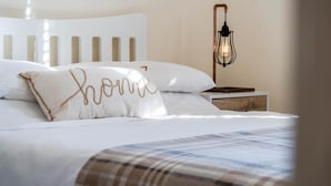 A neatly made bed with white linens and a plaid throw blanket. - Ty George - 3 Bedroom Cottage - Tenby (Tenby)