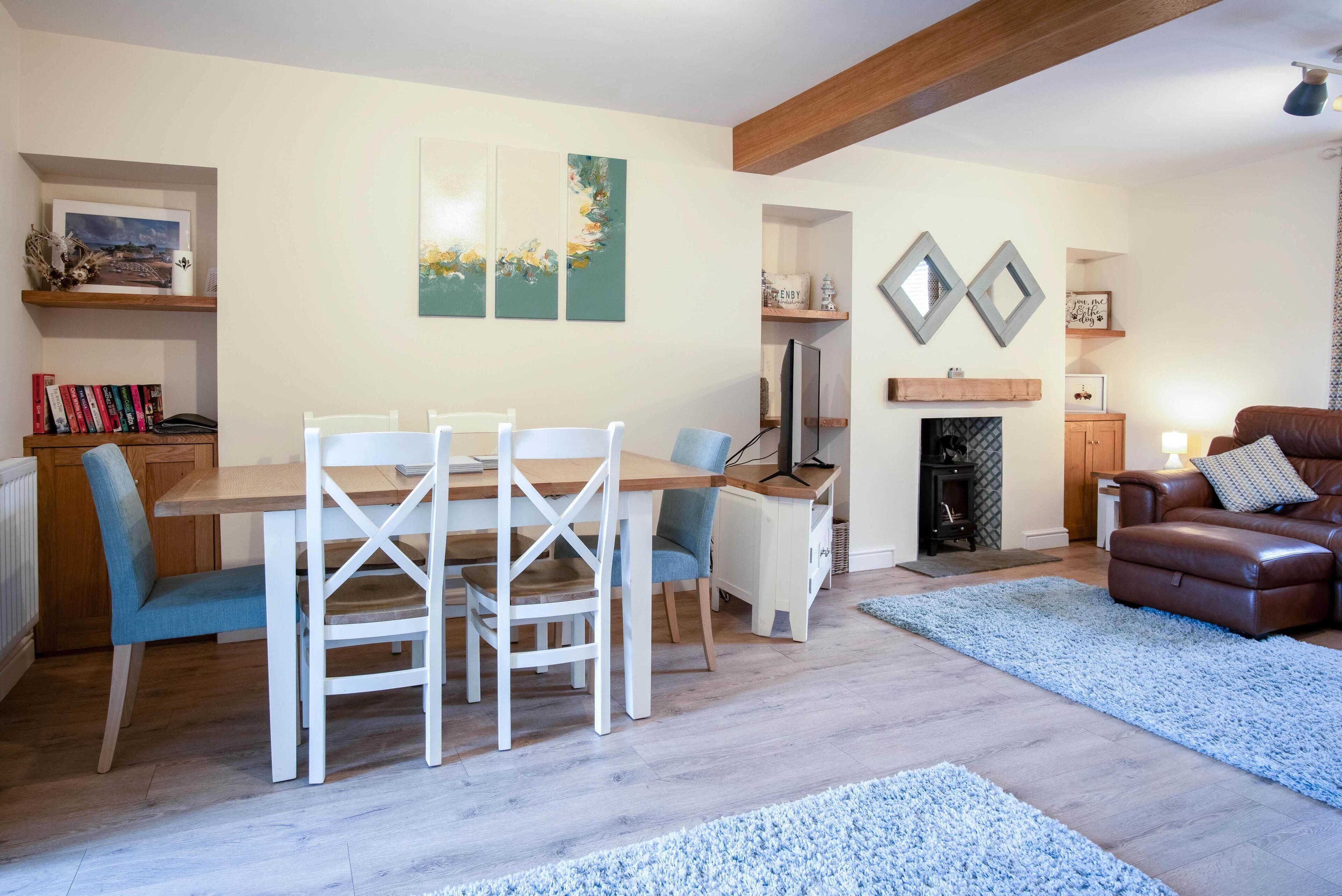 Un salon comprenant une table à manger, des chaises, une cheminée, un canapé et des œuvres d’art accrochées aux murs.