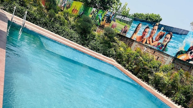 Une piscine d’un bleu éclatant, avec une fresque représentant des personnes en arrière-plan.