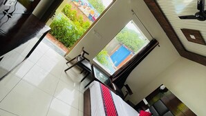 Une chambre d’hôtel moderne, dotée d’un grand lit, d’un bureau et offrant une vue sur la verdure environnante.