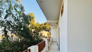 Un long balcon étroit, doté d’un sol carrelé et d’une rambarde rouge.