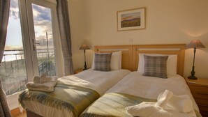 Een hotelkamer met twee bedden, uitzicht op het omliggende landschap en een schilderij aan de muur.