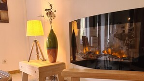 Ein modernes Wohnzimmer mit einer Holzbank, einem kleinen Tisch mit Lampe und einem großen abstrakten Gemälde.