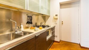 A kitchen with a stainless steel sink, a gas stove, and wooden cabinets.