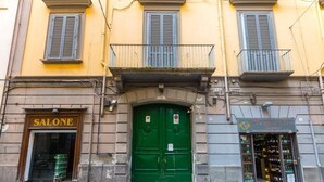 A building with a green door, a sign reading "SALONE", and a shop with shelves of bottles.