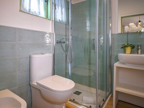 A modern bathroom with a glass-enclosed shower, a toilet, and a sink with a potted orchid. - Hotiday Milano Marittima Pineta (Cervia)