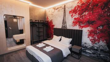 Quarto moderno com cama grande, mesa de cabeceira, espelho e guarda-roupa.
