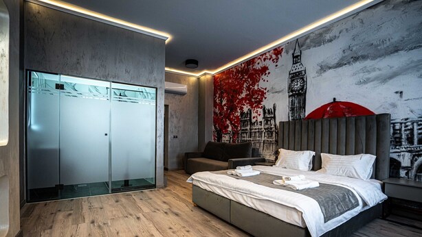 A modern bedroom with a large bed, a wardrobe, and a mural of a cityscape. - City Boutique Hotel Reghin (Reghin)