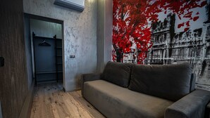 A modern living room with a grey sofa, wooden flooring, and a red abstract painting on the wall. - City Boutique Hotel Reghin (Reghin)