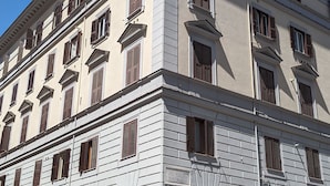 Een meerlaags gebouw met een klassieke architectuur, met een symmetrische gevel en gelijkmatig verdeelde ramen en luiken.