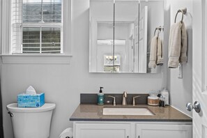 Une salle de bain avec des toilettes, un lavabo et un miroir.