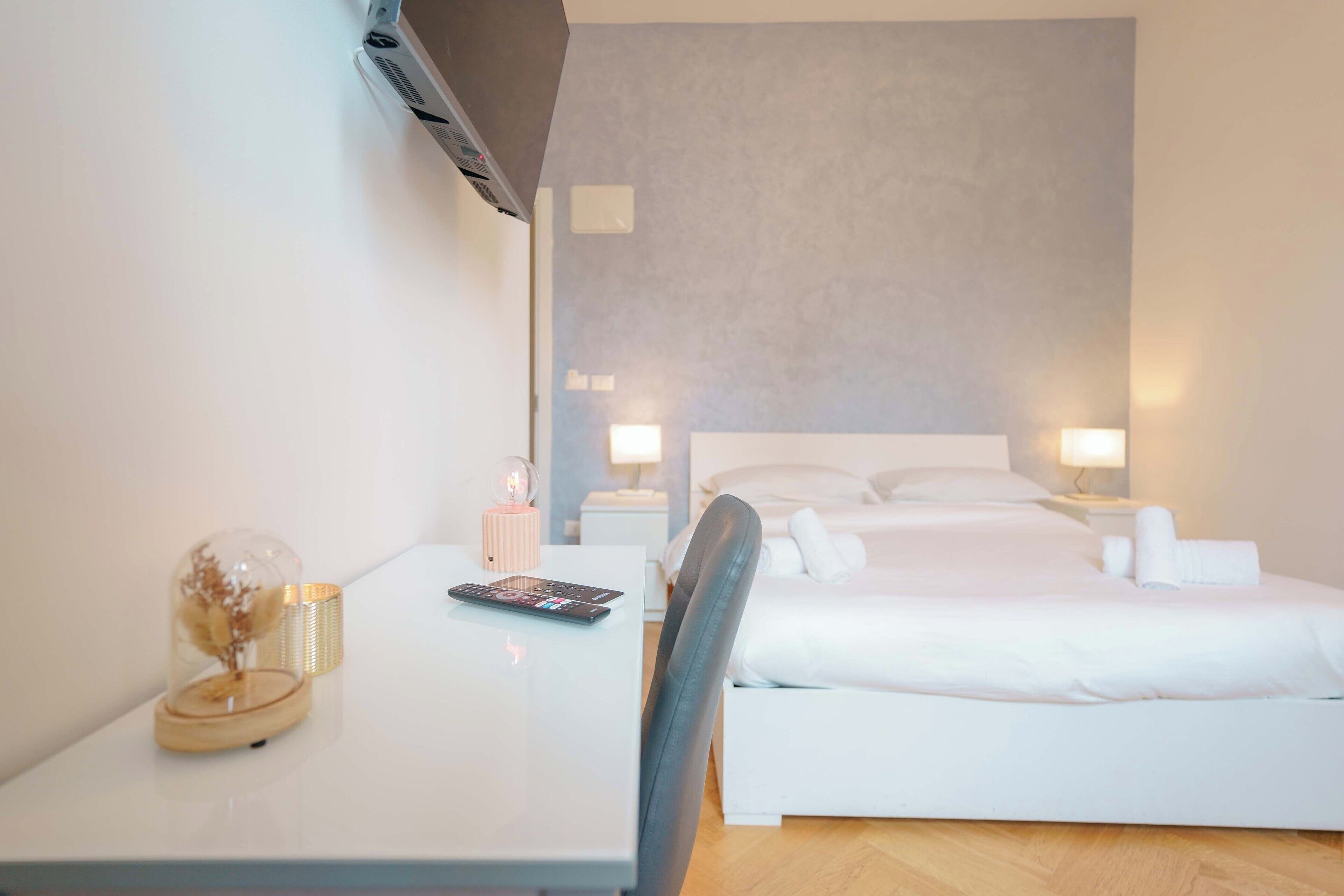 A hotel room with a bed, bedside tables, a desk with a lamp, and a small decorative item on the desk.