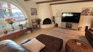 A living room with a fireplace, a television, and a sofa. - Charming Mesa Golf Course Home (Mesa)