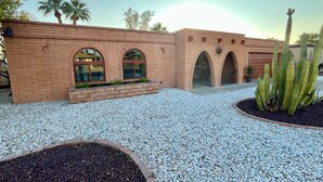 A building with brick walls, arched windows, and a gravel courtyard. - Charming Mesa Golf Course Home (Mesa)