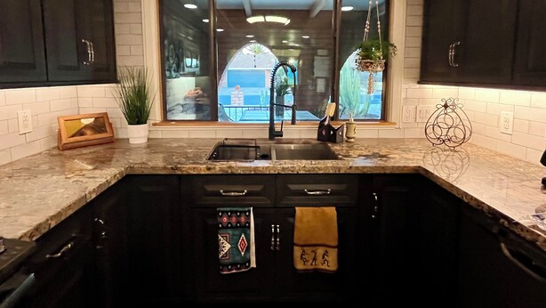 A modern kitchen with dark cabinets, a large window, and a view of the outside. - Charming Mesa Golf Course Home (Mesa)