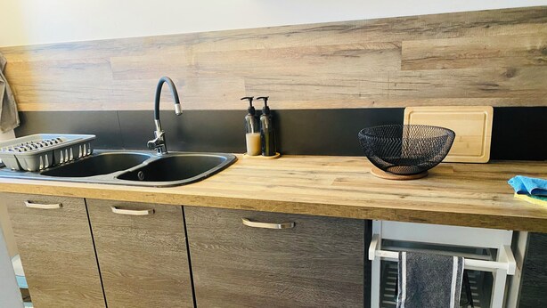 Una cocina con un lavamanos doble, encimera de madera y un mueble de almacenamiento empotrado abajo.