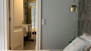 Une chambre à coucher avec un lit, une lampe de chevet et une vue sur la salle de bain.