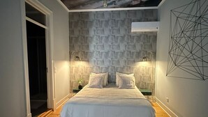 Une chambre dotée d’un grand lit, d’une fresque murale au plafond et d’une œuvre d’art géométrique accrochée au mur.