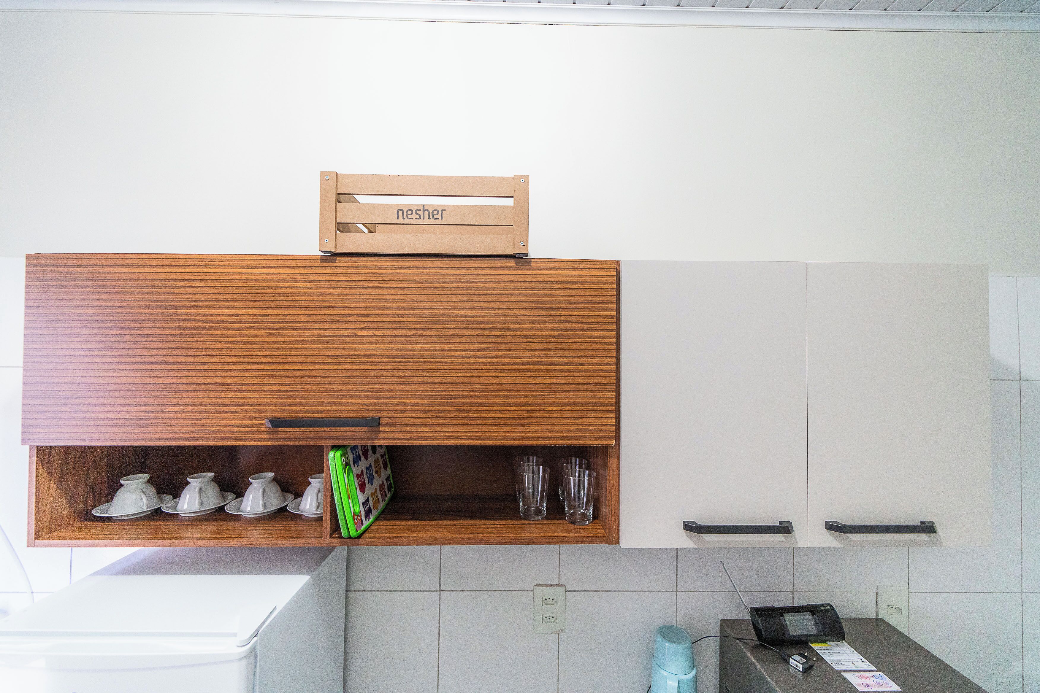 A kitchen with wooden cabinets, a built-in shelf with cups and glasses, and a sign above the shelf.