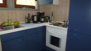 A compact kitchen with a stove, sink, and blue cabinets. - Ferienhaus im Ferienpark Mirow (Mirow)