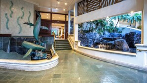 A lobby with a large aquarium, a staircase, and a view of a tropical garden. - Waikiki Retreat at Ilikai Hotel | Near Beach and Ala Moana (Honolulu)