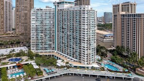 A high-rise hotel with multiple floors, a swimming pool, and a landscaped area with palm trees. - Waikiki Retreat at Ilikai Hotel | Near Beach and Ala Moana (Honolulu)