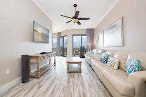 A spacious living room with a sofa, coffee table, and a dining area with a wooden table and chairs. - Gulf Coast Paradise Phoenix X 102 (Orange Beach)