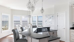Una cocina moderna con una isla grande, armarios blancos y vista al océano.