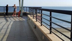 A seaside promenade with a concrete walkway, metal railing, and a view of the ocean. - Boqueirão studio apartment in Santos, building facing the beach with partial view (Boqueirão Santos)