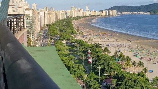 A coastal cityscape with a beach, high-rise buildings, and a green park area. - Boqueirão studio apartment in Santos, building facing the beach with partial view (Boqueirão Santos)