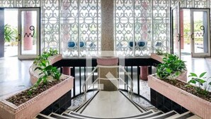 A lobby with a central column, two potted plants, and a patterned floor. - Boqueirão studio apartment in Santos, building facing the beach with partial view (Boqueirão Santos)