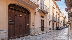 A narrow cobblestone street with historic buildings, a large wooden door, and parked cars. - Casa Sant Agata con Terrazza by Wonderful Italy (Palermo)