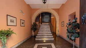 A hallway with a marble floor, framed pictures on the walls, and a staircase with a wooden railing. - Casa Sant Agata con Terrazza by Wonderful Italy (Palermo)