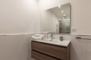 A modern bathroom with a large mirror, white tiles, a wooden vanity, and a towel rack. - Casa Sant Agata con Terrazza by Wonderful Italy (Palermo)