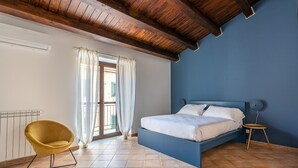 A bedroom with a bed, a chair, and a window with curtains. - Casa Sant Agata con Terrazza by Wonderful Italy (Palermo)
