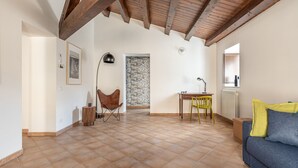 A spacious living area with a high ceiling, a sofa, a chair, a table, and a radiator. - Casa Sant Agata con Terrazza by Wonderful Italy (Palermo)