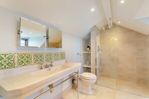 A bathroom with a large mirror, a sink, a toilet, and a shower. - 6 Bed in Lee (oc-d30327) (Ilfracombe)