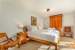 A hotel room with a wooden bed, a wooden chair, a nightstand, a wardrobe, and a small table with a chair. - 6 Bed in Lee (oc-d30327) (Ilfracombe)