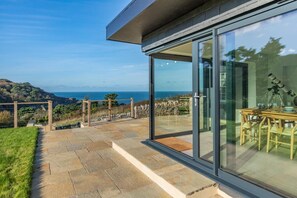 A modern house with a glass patio overlooking a coastal landscape.