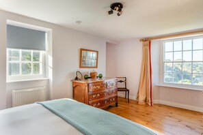 A bedroom with a large bed, a dresser, a chair, and a window with a view.