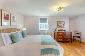 A bedroom with a bed, dresser, chair, and artwork on the walls.