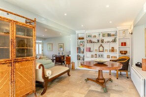 A spacious living area with a dining table, a sofa, a bookshelf, and a large wooden cabinet. - 6 Bed in Lee (oc-d30327) (Ilfracombe)