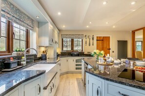 A modern kitchen with white cabinets, granite countertops, and a central island with a sink. - 4 Bed in Axminster (oc-s30365) (Axminster)