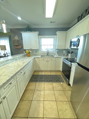 A modern kitchen with white cabinets, a stainless steel refrigerator, and a built-in oven.