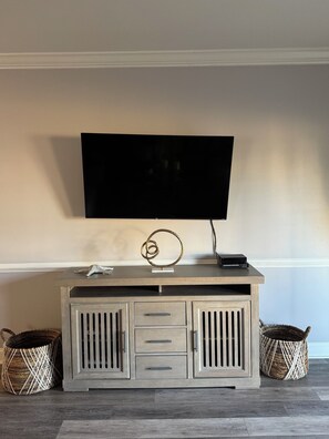 A flat-screen TV mounted on a wall above a wooden console with drawers and a decorative object.
