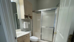 A bathroom with a toilet, sink, mirror, and shower. - Modern Retreat, 3BR Condo in Myrtlewood Villas! (Myrtle Beach)