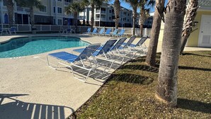 A pool area with lounge chairs and palm trees. - Modern Retreat, 3BR Condo in Myrtlewood Villas! (Myrtle Beach)