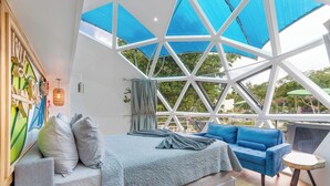 Un dormitorio moderno con una cama grande, un sofá azul y una mesita pequeña.