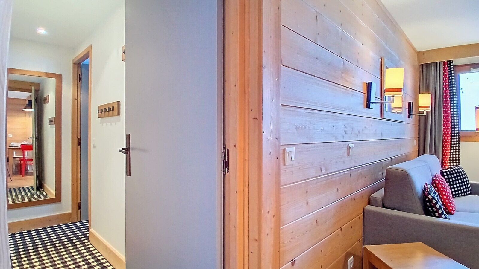 A hotel room with a checkered floor, a wooden panel wall, a sofa, and a window with curtains.