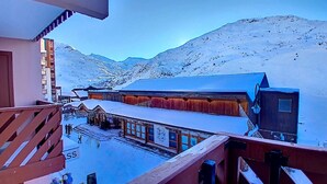 A snow-covered building with a wooden exterior and a blue roof, surrounded by snow-covered mountains. - (1.208) Superbe T2 plein sud aux Ménuires (Les Menuires)